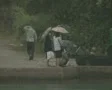 Zoom out from people in rain to swimming pool and garden SD Footage