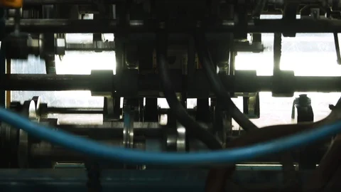 Zoom out of a printing press dropping magazines onto a conveyor belt Stock Footage 130144380