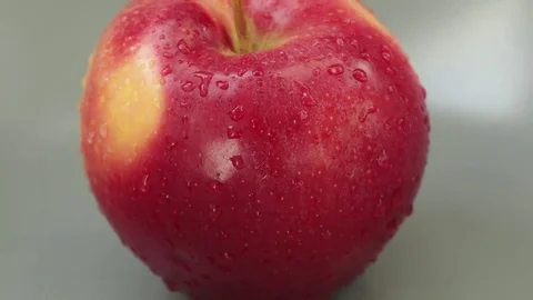 Zoom out on red apple with water drops on it on a grey plate Stock Footage 80375337