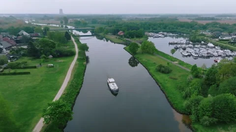 Zoom out revealing barge navigating green canal banks near marina Stock Footage 311903577