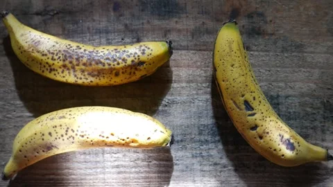 A zoom-out reveals bananas on a table. Random sunbeams move across the fruit Stockbeeldmateriaal 345847088