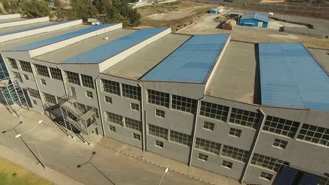 Zoom out shot of a large building a blue corrugated iron on the roof Stock-Footage 107923399