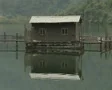 Zoom out from small building over peaceful lake SD Footage
