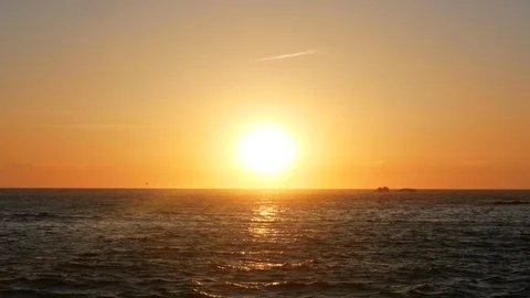 Zoom out from sun at sunset over the ocean with light reflecting Stock Footage 107996613