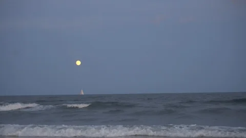 Zoom out, then rack focus Moon over ocean Stock Footage 98909799