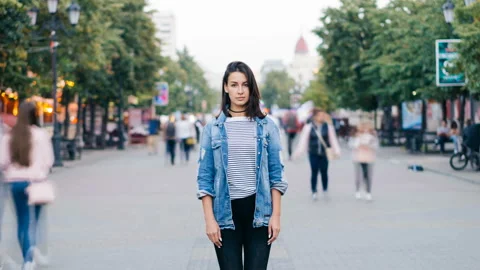 Zoom out time-lapse of beautiful lady with dark hair standing alone among crowd Stock Footage 94982285