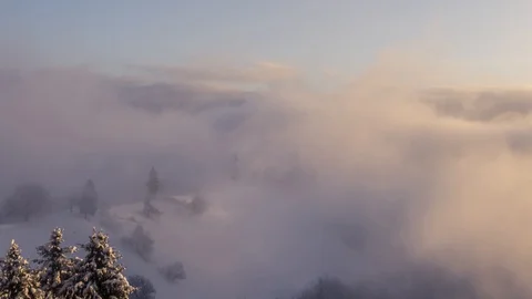 Zoom out time lapse low altitude inversion clouds rolling over snow covered hill Stock Footage 129092536