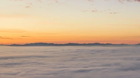 Zoom out time lapse over sea of clouds. Colorful vivid sunrise Stock Footage 129029454