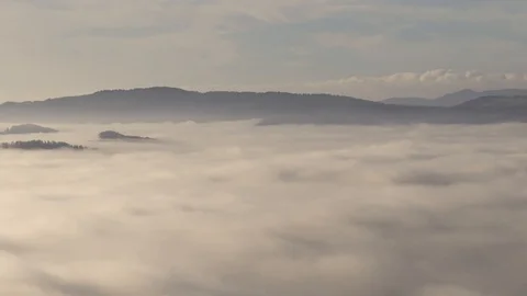 Zoom out time lapse over inversion clouds. Low fog clouds moving over valley Stock Footage 129053943