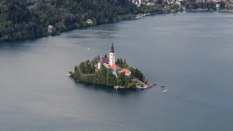 Zoom out time lapse of spring lake Bled island snow covered mountains Stock Footage 129029321