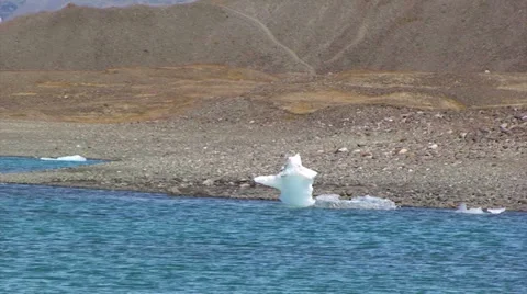 Zoom out from tiny iceberg by the shore to show full lake 스톡 동영상 37972091