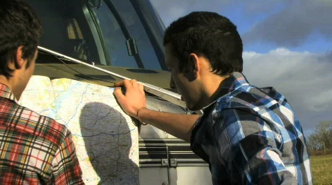 Zoom out on two boys reading map on van Video stock 541509
