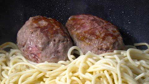 Zoom out. Two cutlets and a side dish - pasta noodles - are fried in boiling  스톡 동영상 149354660