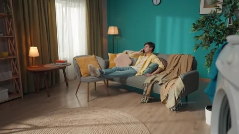 Zoom out video capturing a dark-haired man sitting on the couch, casually Stock Footage 252388674