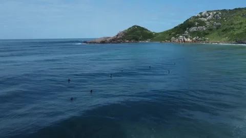 Zoom out view to beatiful ocean coast with big rocks and stones and surfers Stock Footage 272377746