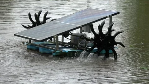 Zoom out view of solar panels powering two water wheels to pump water away 4k Stock Footage 256589847