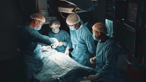 Zoom out view at the surgeon operating patient with helping of assistants while Stock Footage 144854831