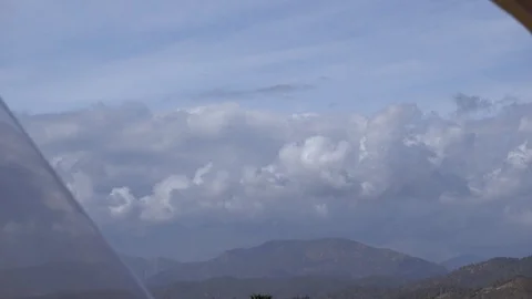 Zoom out view from window on the clouds and mountains above village Stock Footage 89872589