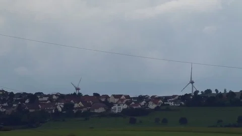 Zoom out: Wind turbines, small German rural village, pastures, rain clouds Video stock 80088204