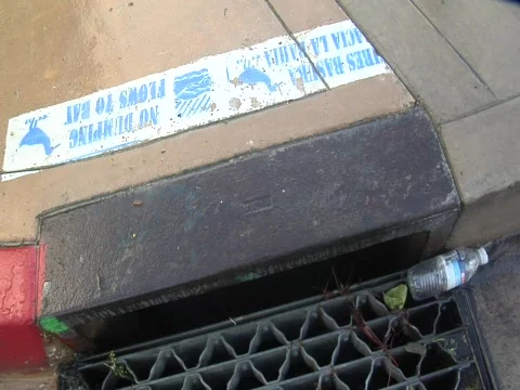Zoom to a plastic bottle about to fall into storm drain Video stock 609678