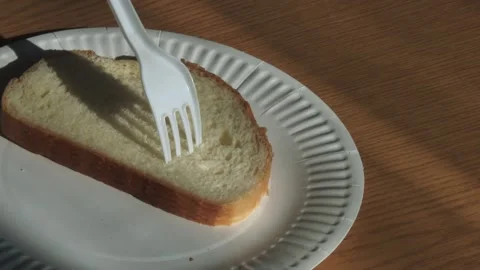 Zoom on a plastic fork stuck into bread on a paper plate in warm light. Stock Footage 348403136