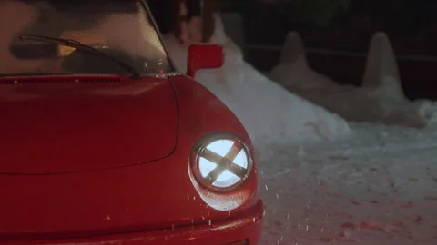 Zoom in shining crossed front car headlight of red convertible, snow falling Stock Footage 196820168