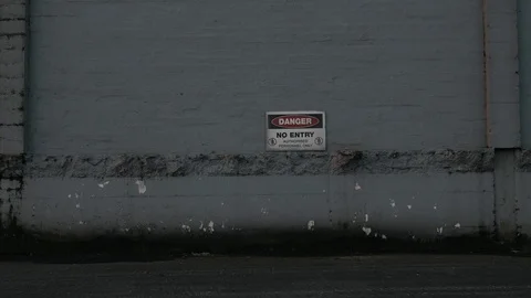 Zoom in shot of a Danger, no entry sign on a grey wall, industrial area Vídeos de archivo 106356496