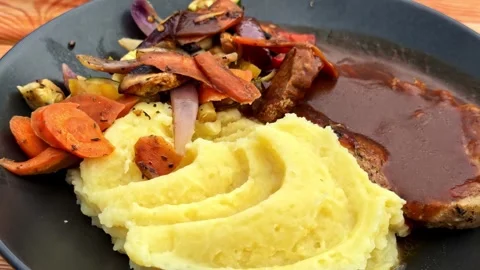Zoom in Shot of Dinner Plate with Mashed Potatoes Gravy Meat and Vegetables Stock Footage 340858985