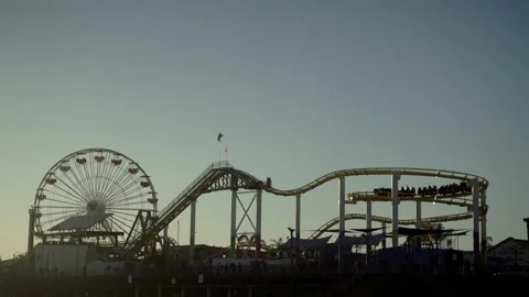 Zoom shot of Roller coaster on the Santa Monica pier during sunset Видео 261079004