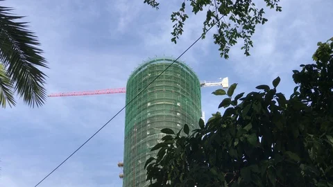 Zoom In Shot of Skyscraper Construction Site Behind the Trees Stock Footage 100981792