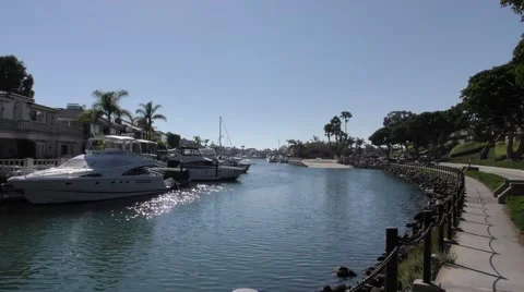 Zoom in on a Small finger in the harbor oceanfront homes with their yachts an Stock Footage 67679566