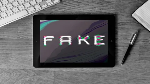Zoom in a tablet put on a desk with word FAKE on glitch computer bug background Stock Footage 119295219