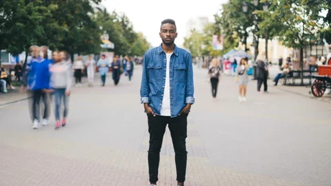 Zoom in time-lapse of unhappy single African American guy standing alone in the Stock Footage 95032819
