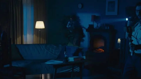 Zoom in video capturing two ghost hunters entering a dark room in search for an Stock Footage 252381261