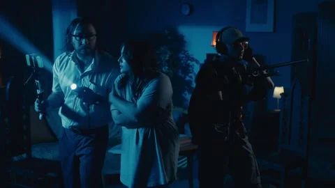 Zoom in video capturing two ghost hunters and a victim going around the room in Stock Footage 252381491