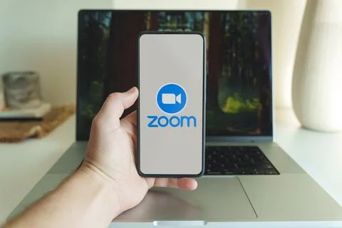 Zoom video chat application logo in front of laptop Stock Photos