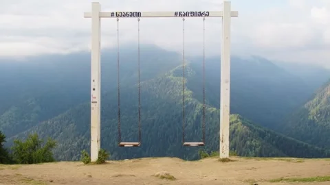Zoom in view Iconic giant empty wooden swings at Heshkili huts viewpoint in.. Stock-Footage 332058416