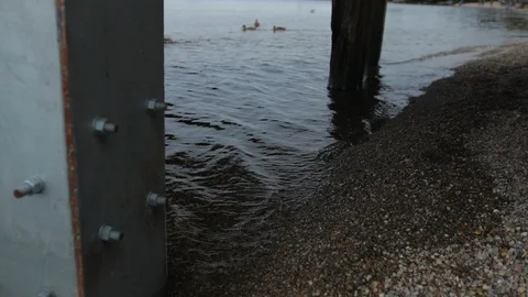 Zoom in on the water lapping against the beach under the pier Stock-Footage 100573740