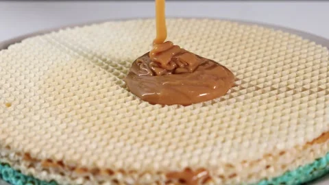 Zoomed-in view of caramelized condensed milk dripping onto waffle layers Stock Footage 297670437