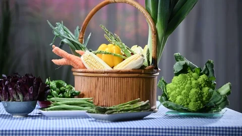 Zooming in a basket of fresh vegetables surrounded by several plates with ass Stock Footage 123451689
