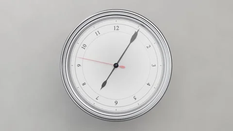 Zooming camera toward round clock on light gray wall, red second hand sweeping Stock Footage 337505104