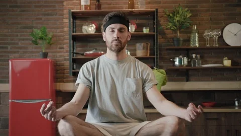 Zooming in close up view of young man meditates while practicing yoga in lotus Stock Footage 111959525
