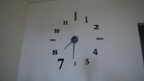 Zooming in huge wall clock decorated with numbers and words with arrows showing Stock Footage 277076793