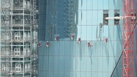 Zooming in o a group of workers cleaning the windows of a high rise building, Stock Footage 114645448