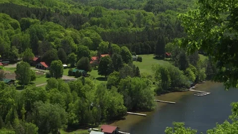 Zooming out on cabins and docks on a lake surrounded by forest Stock Footage 322139698