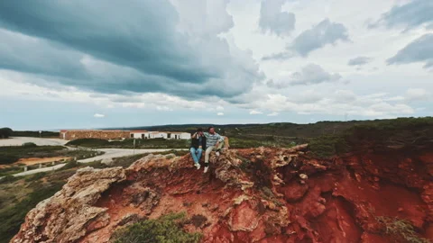 Zooming out shot by drone featuring two men sitting on top of the cliffs Stock Footage 203595349