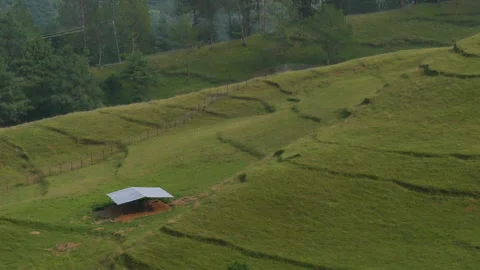 Zooming out of a small building structure to a green hill with layers and gr Stock Footage 249394325