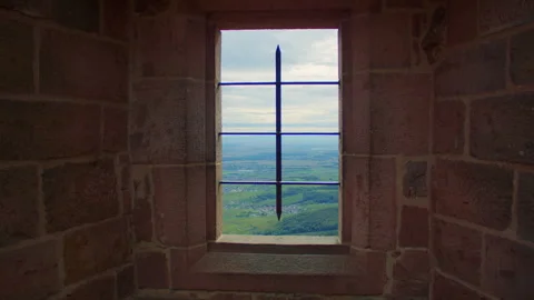 Zooming in through a grated window of a medieval tower towards a green valley Stock Footage 311887248