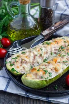 Zucchini boats stuffed with ground meet on cast iron pan Stock Photos