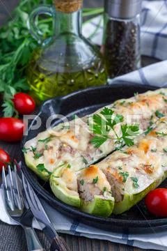 Zucchini boats stuffed with ground meet on cast iron pan Stock Photos